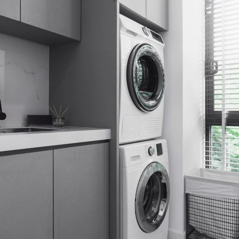 A grey and white utility room with stacked integrated washer and dryer.